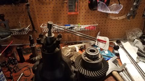 1985 Ford Bronco - Differential gears and a bearing are laid out on a workbench with various tools, including a torque wrench, suggesting a repair or assembly…