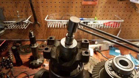 1985 Ford Bronco - Close-up of differential gears and bearings on a workbench, with a tool engaged.