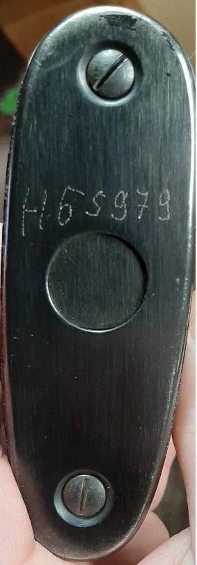 2003 Ford F-250 - A close-up view of a gun stock butt plate, showing etched markings and screw heads.