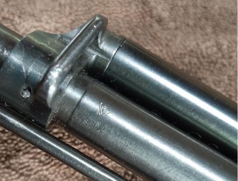2003 Ford F-250 - A close-up view of a metal component, possibly from a vehicle, showing stamped markings and a securing clip.