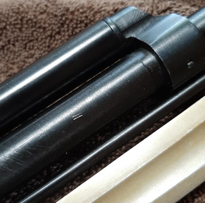 Close-up of a black metal part with two small parallel lines etched into it