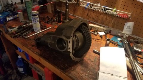 1985 Ford Bronco - A disassembled differential sits on a workbench surrounded by various tools and automotive parts.