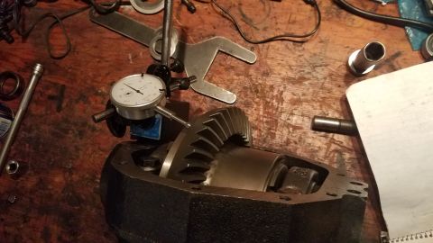 1985 Ford Bronco - Dial indicator measures differential gears on a wooden workbench, surrounded by tools and parts.