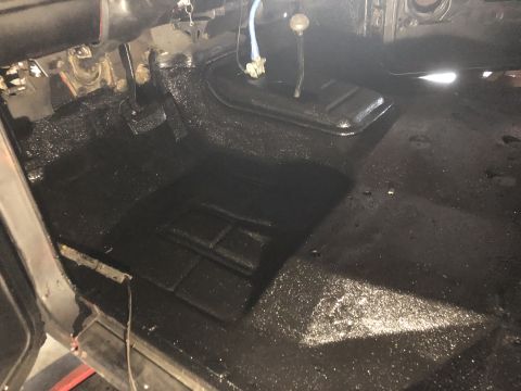 1978 Ford Bronco - The interior floor of a vehicle has been coated with a black protective spray liner.