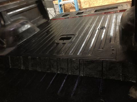 1978 Ford Bronco - Interior of a truck bed, showing the ribbed floor and wheel well, painted black.