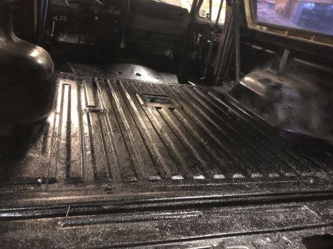1978 Ford Bronco - The interior of a vehicle shows a black ribbed floor and a roll cage.