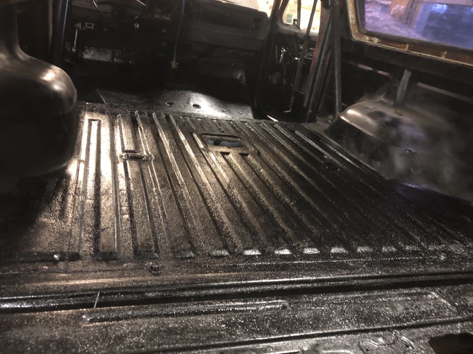 Black interior of a vehicle with ribbed flooring and roll cage visible