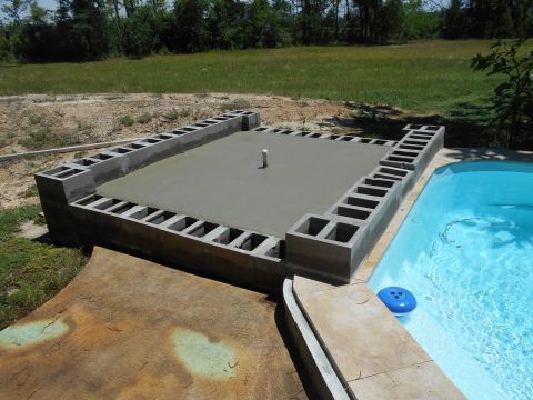 1992 Ford Bronco - Construction of a concrete pool deck is underway, cinder block forms and freshly poured cement adjacent to a swimming pool.
