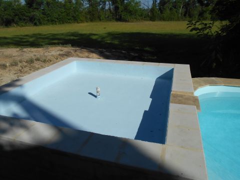 1992 Ford Bronco - An empty swimming pool with a pipe in the middle is adjacent to a filled pool under a sunny sky.
