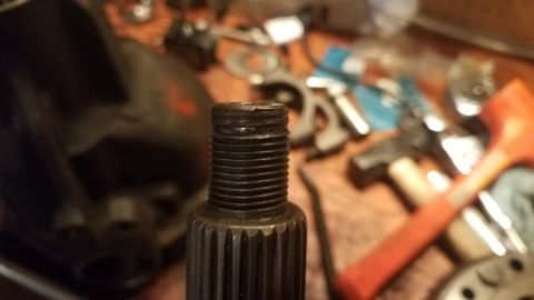 1985 Ford Bronco - A close-up shot of a threaded shaft with splines, with various tools scattered in the background.