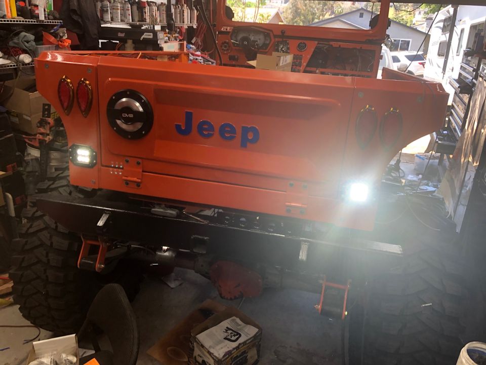 Orange Jeep body with "Jeep" in blue letters, aftermarket bumper, and large tires