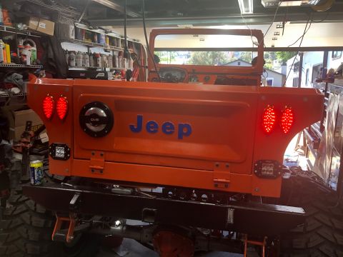 1992 Jeep Wrangler - Rear view of an orange Jeep CJ-7 with custom modifications, including LED lighting and a heavy-duty bumper.