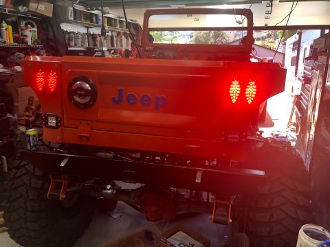 1992 Jeep Wrangler - This orange Jeep Wrangler features custom LED tail lights and prominent "Jeep" badging on the rear panel.