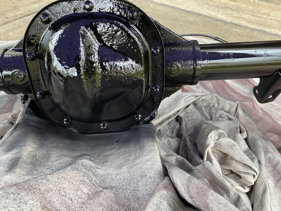 Black painted differential housing and axle tube on a gray cloth.