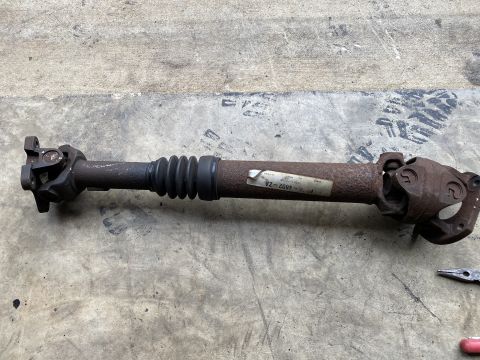 1994 Ford Bronco - A rusty driveshaft with a rubber boot and two U-joints is laid out on a concrete surface. A white label with black text is attached to the…