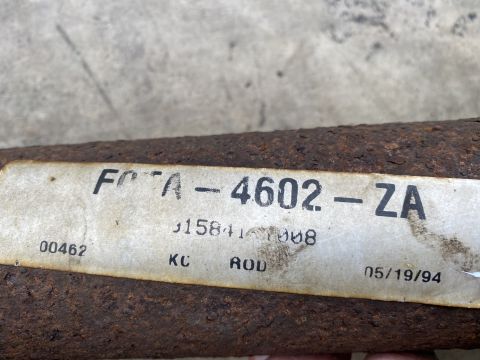 1994 Ford Bronco - A close-up of a rusty metal rod with a white label showing part number FOTA-4602-ZA and a date of 05/19/94.