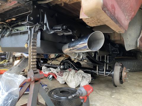 1994 Ford Bronco - The underside of a vehicle is shown with a new exhaust system installed. The rear axle, leaf springs, and brake drum are visible, along wit…
