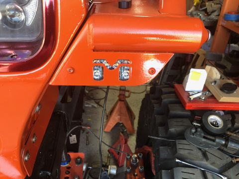 1992 Jeep Wrangler - A close-up view of the front fender area of an orange Jeep Wrangler shows custom "M" shaped LED lights integrated into the bodywork. The ve…