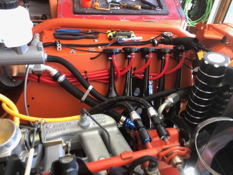1992 Jeep Wrangler - A close-up view of an engine bay with multiple red hoses and black braided lines connected to various components. The engine components are…