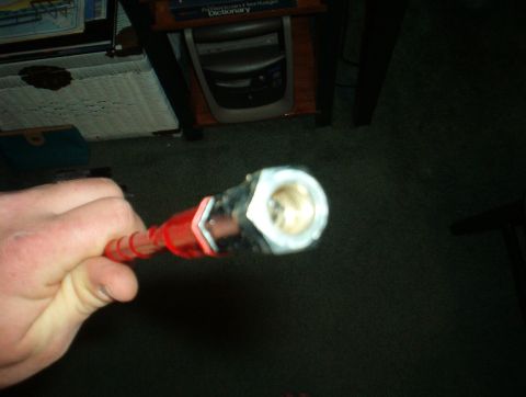 1988 Ford Bronco - A hand holds a red automotive part with a metal fitting, likely a hose or cable end.