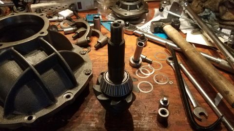 1985 Ford Bronco - A collection of automotive differential parts and tools are laid out on a wooden workbench. Visible parts include a differential housing, a…