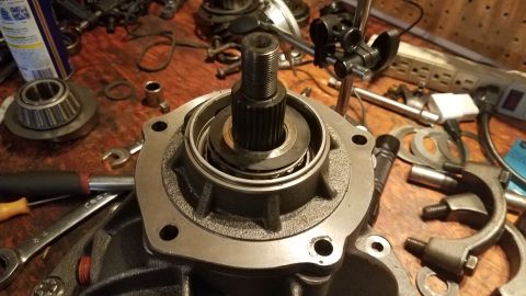 1985 Ford Bronco - A close-up view of a vehicle's differential housing with a splined shaft and bearing assembly installed. Various tools, including wrenches…