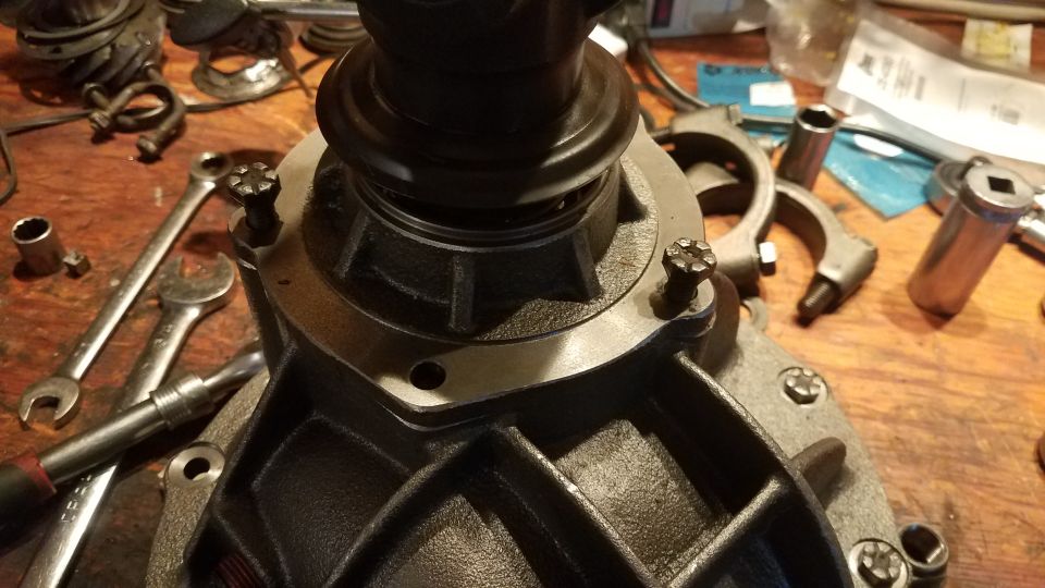 Differential housing with bolts and wrenches on a workbench.