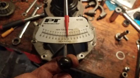 1985 Ford Bronco - A torque wrench is being used on a differential housing, with various tools scattered on a wooden workbench.