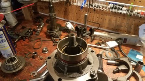 1985 Ford Bronco - A close-up view of a vehicle's differential or transmission part being worked on, with various tools and components scattered on a wooden w…