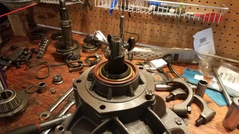 1985 Ford Bronco - A close-up view of a vehicle's differential or transmission housing on a workbench, surrounded by various tools and disassembled parts. The…