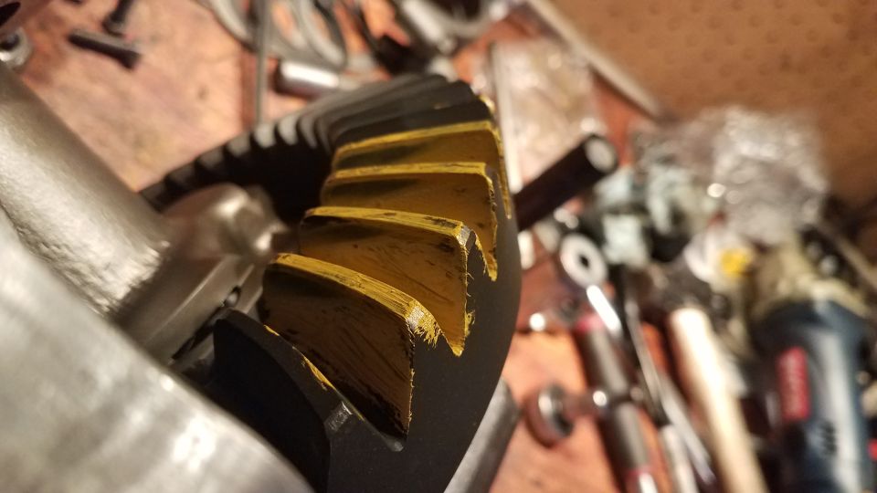 Close-up of a black and yellow differential gear with wear marks on teeth.