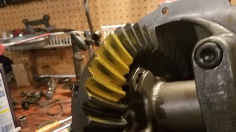 1985 Ford Bronco - A close-up view shows a yellow-marked ring gear, likely part of a differential assembly, in a workshop setting. Tools and shelving are visi…