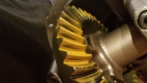 1985 Ford Bronco - A close-up view of a differential gear set with yellow marking compound applied to the teeth. The gears are part of a vehicle's drivetrain,…