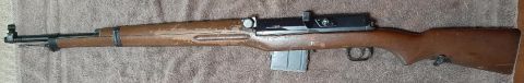 2003 Ford F-250 - A rifle with a wooden stock and a metal magazine is shown lying on a textured surface.