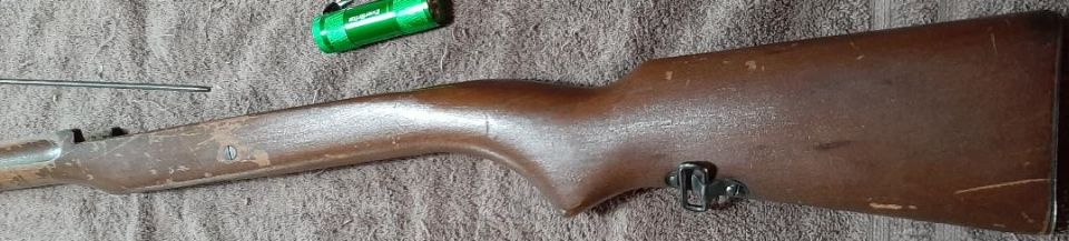 Wooden rifle stock with a green flashlight and metal rod