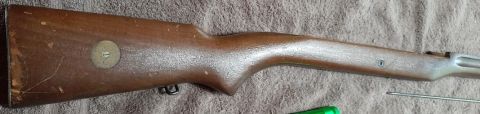 2003 Ford F-250 - The image shows the wooden stock of a rifle. It is a brown wooden stock with some scratches and wear. There is a circular metal plate with…