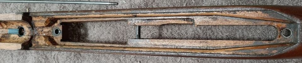 Wooden rifle stock with internal metal components and a metal rod