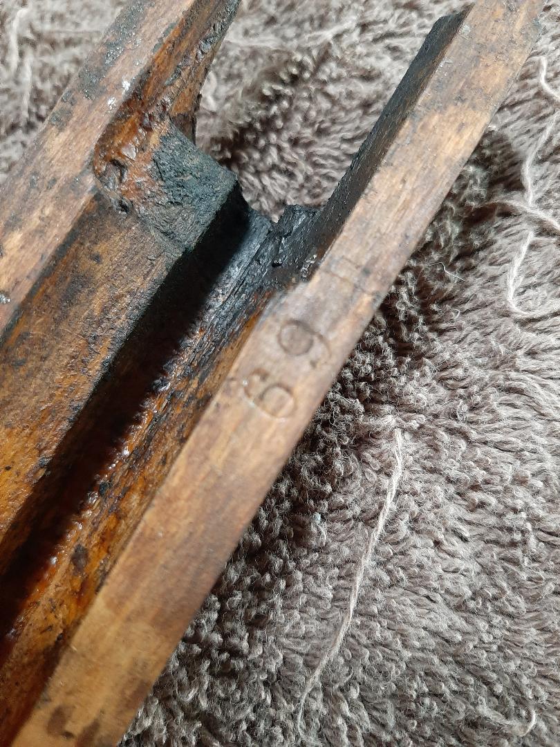 Close-up of a wooden object with "69" carved into it, on a textured surface.