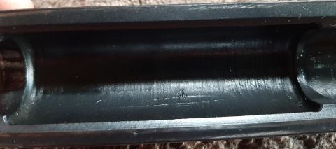 2003 Ford F-250 - A close-up view of the interior of a dark-colored metal part, possibly a firearm receiver, showing a small etched symbol resembling a crown…