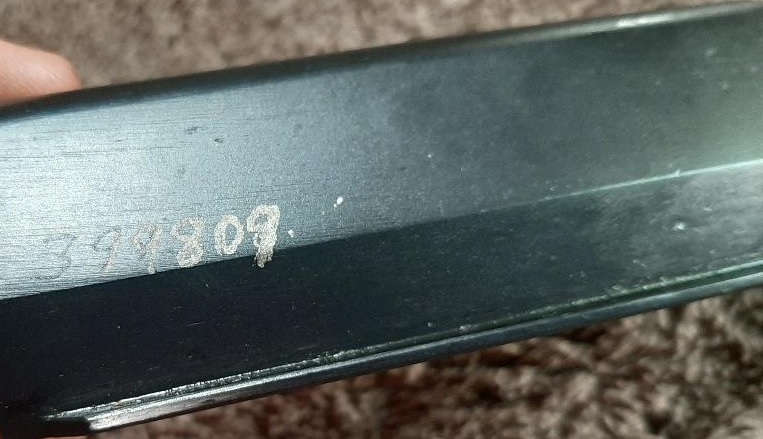Close-up of serial number 3944309 stamped on a dark metal surface.