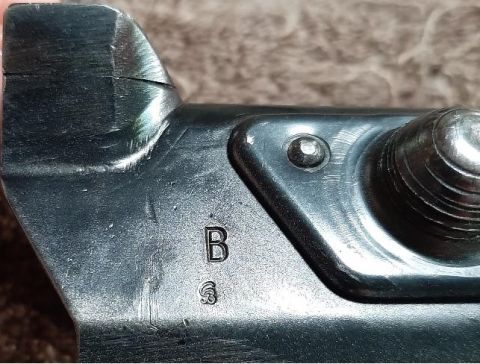 2003 Ford F-250 - A close-up view of a metal part with stamped markings 'B' and a symbol below it. The part appears to be a component of a vehicle, possibly…