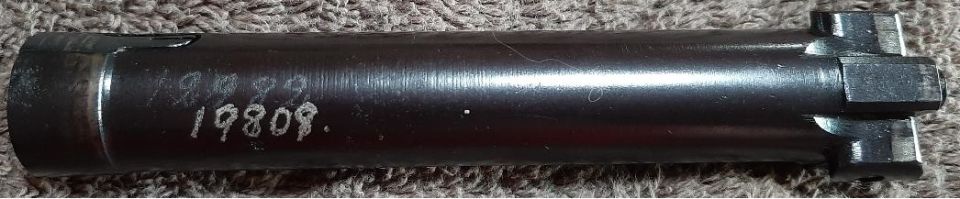 Dark metal part with white markings "19809." and a hexagonal end with prongs.