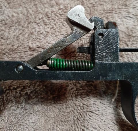 2003 Ford F-250 - A close-up view of a firearm trigger assembly with a green spring.