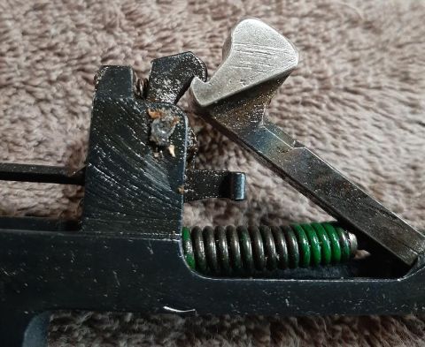 2003 Ford F-250 - A close-up view shows the internal mechanism of a firearm, including a black metal frame, a silver lever, and a green spring.