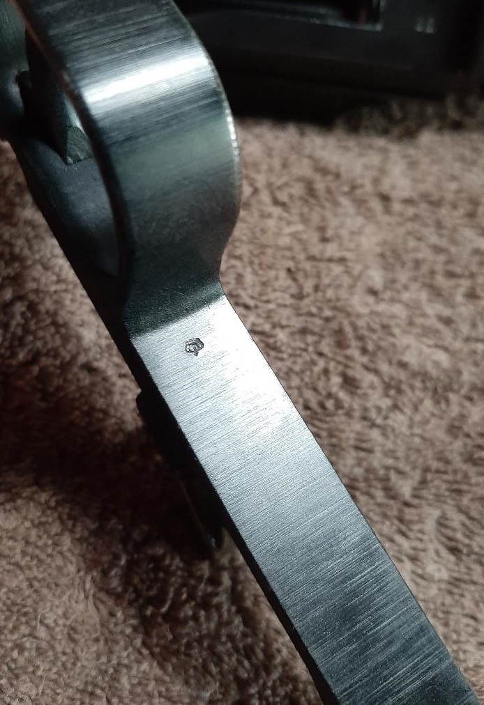 Close-up of a small stamped symbol on a metal vehicle part.
