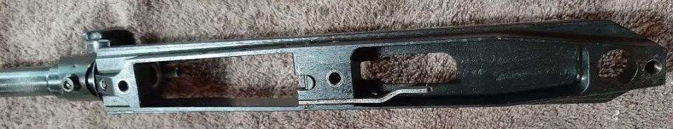 Close-up of a disassembled AR-15 style rifle receiver on a textured surface.