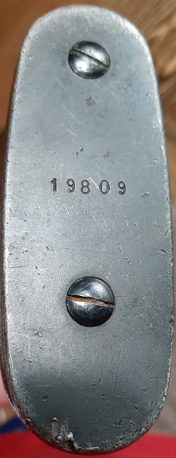 2003 Ford F-250 - The bottom of a metal buttplate is shown, featuring the stamped serial number 19809 and two screws.