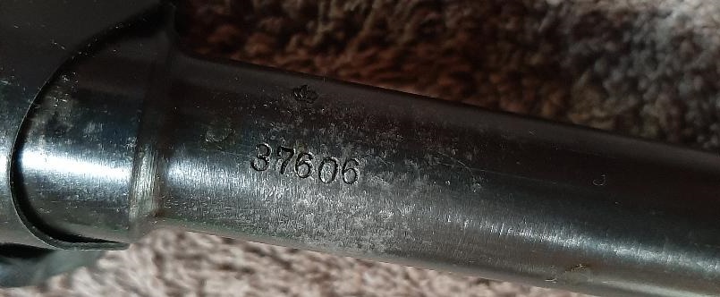 Close-up of the serial number 37606 stamped on a dark metallic surface.