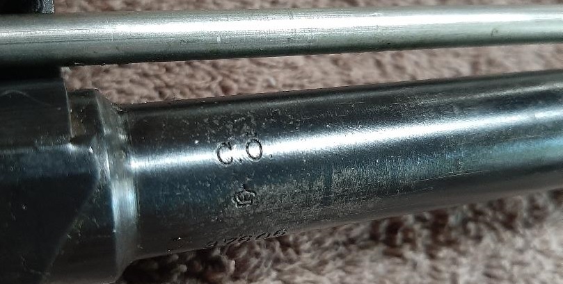 Close-up of metallic part with markings C.O. and a crown symbol.