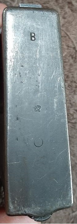 2003 Ford F-250 - A close-up view of the base of a metal firearm magazine, showing a stamped letter 'B' and a small circular indentation.